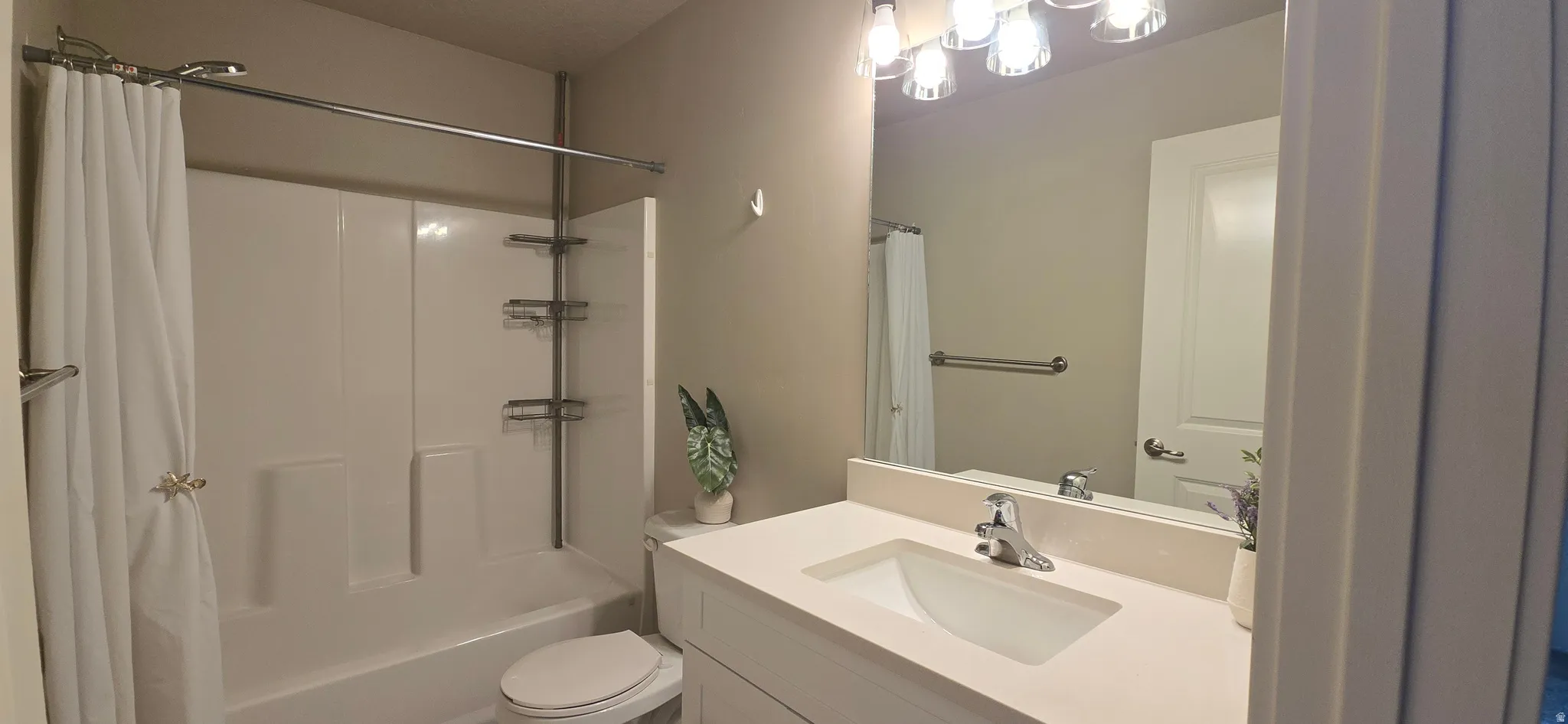 White vanity with integrated sink, polished chrome faucet, and overhead bar lighting
