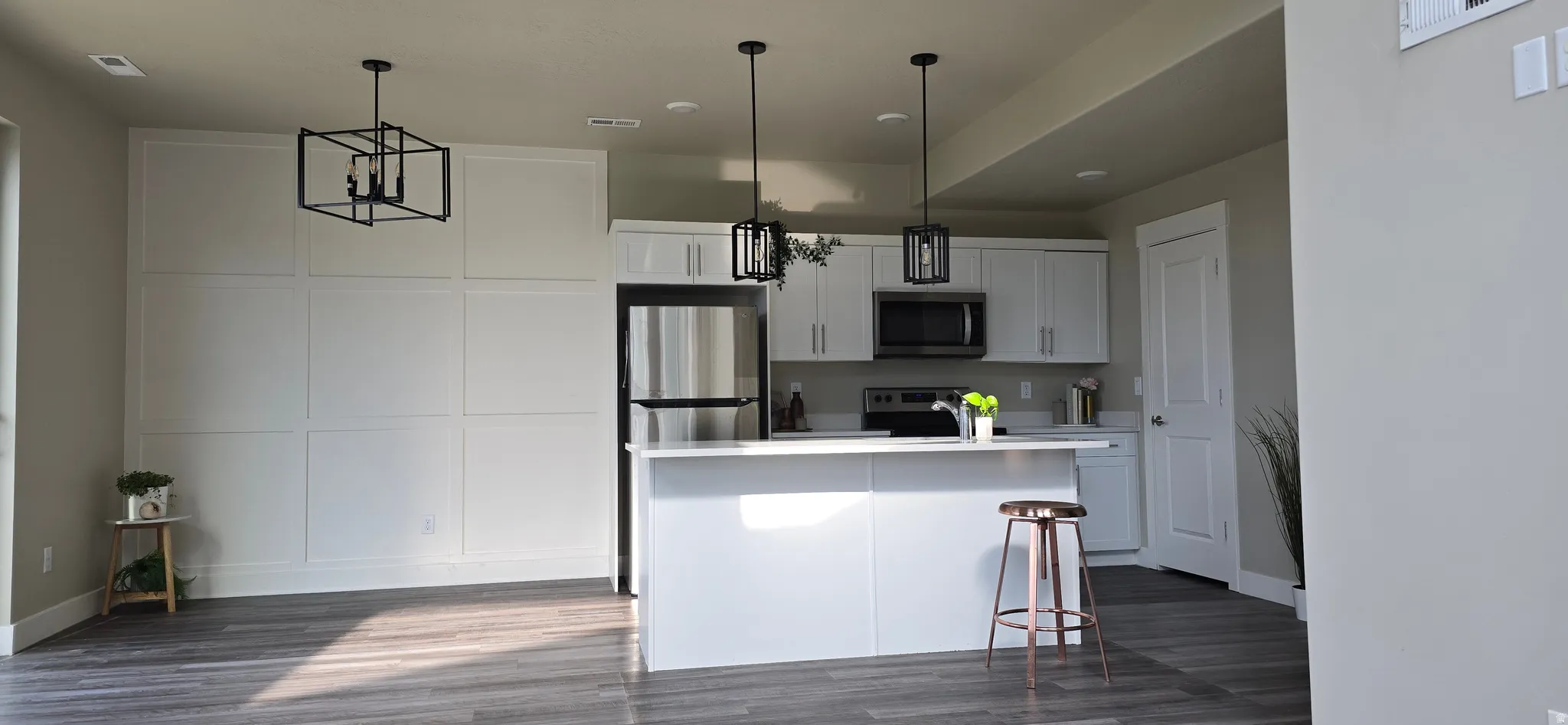 Modern kitchen featuring white cabinetry, stainless steel appliances, and a central island with pendant lighting