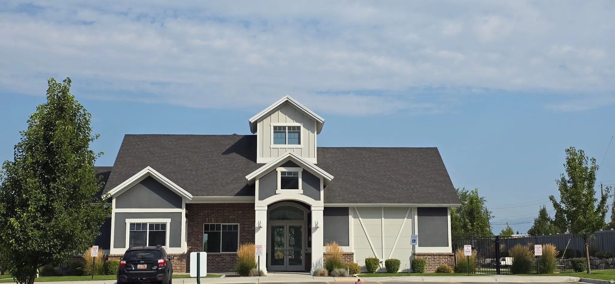 Exterior featuring a gable roof, mixed siding, brick detailing, dormer windows, and a covered entry