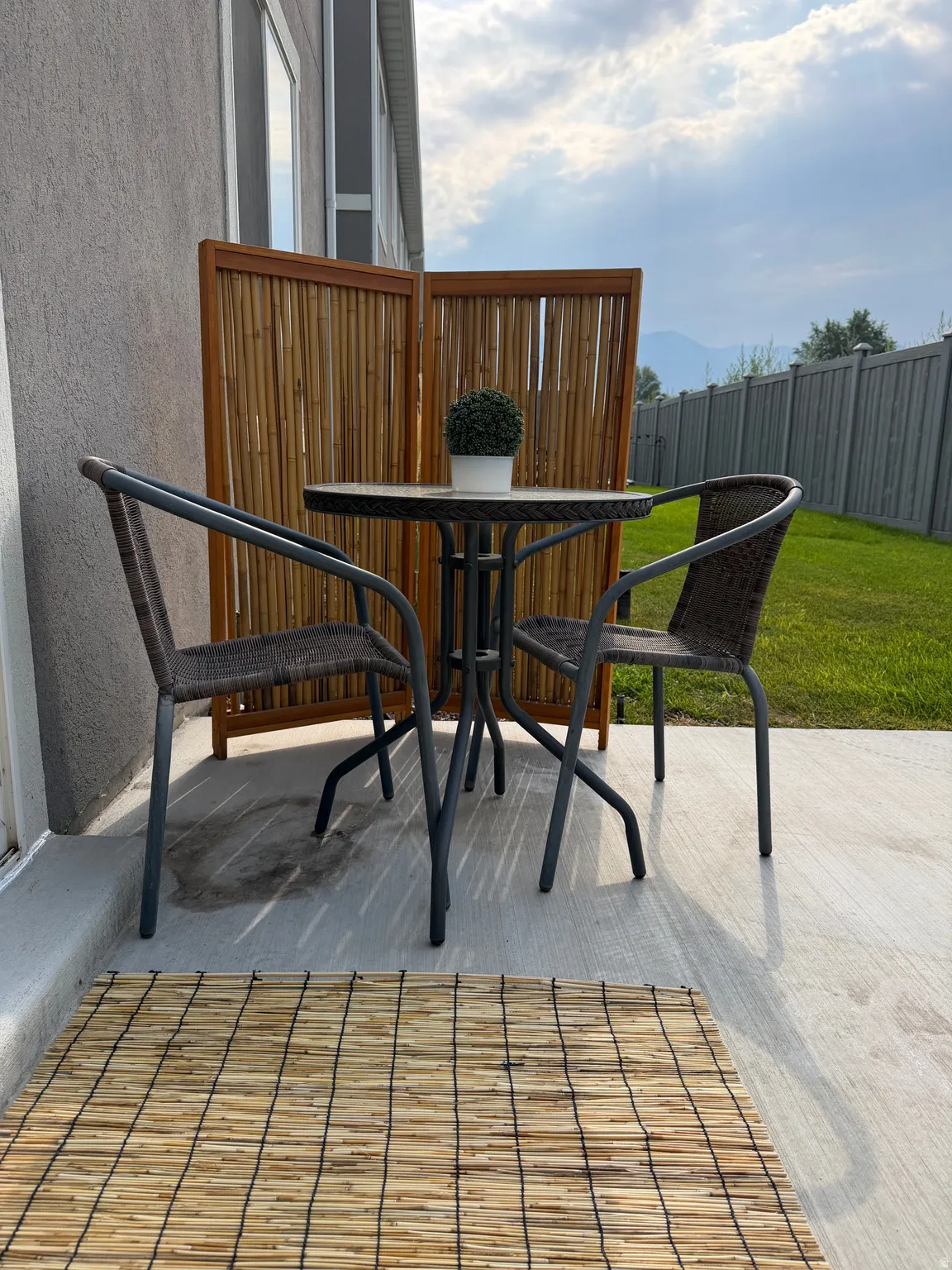 Poured concrete patio with a privacy screen and a manicured lawn