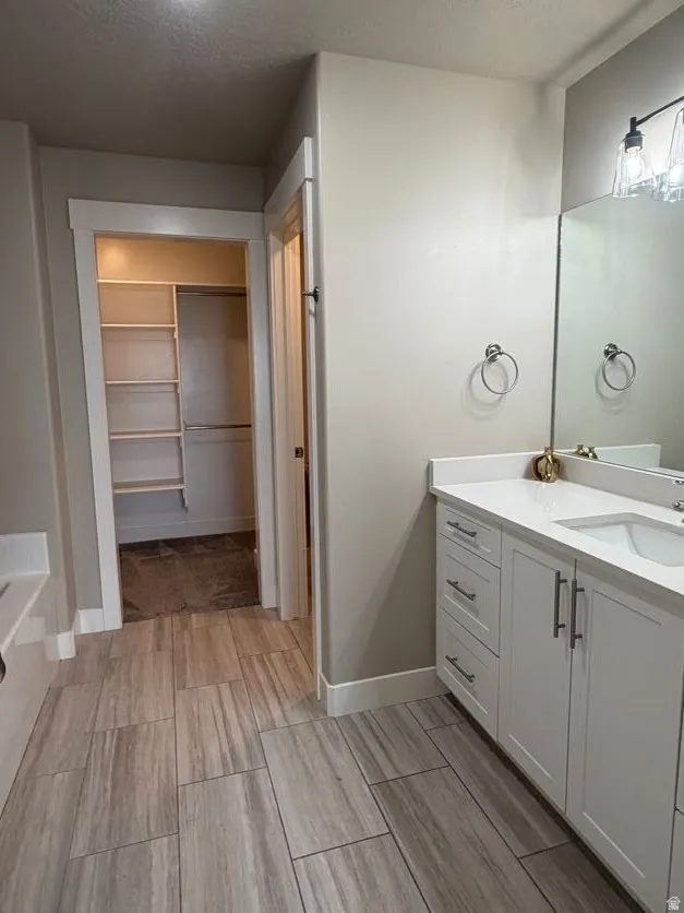 Tile-finish flooring with a dual vanity featuring white cabinetry, integrated sinks, and polished chrome hardware