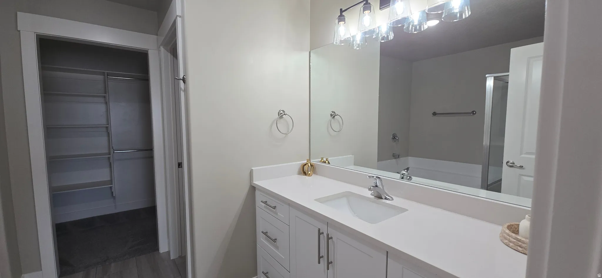 Spacious bathroom featuring a white vanity with integrated sink, large mirror, and contemporary light fixture
