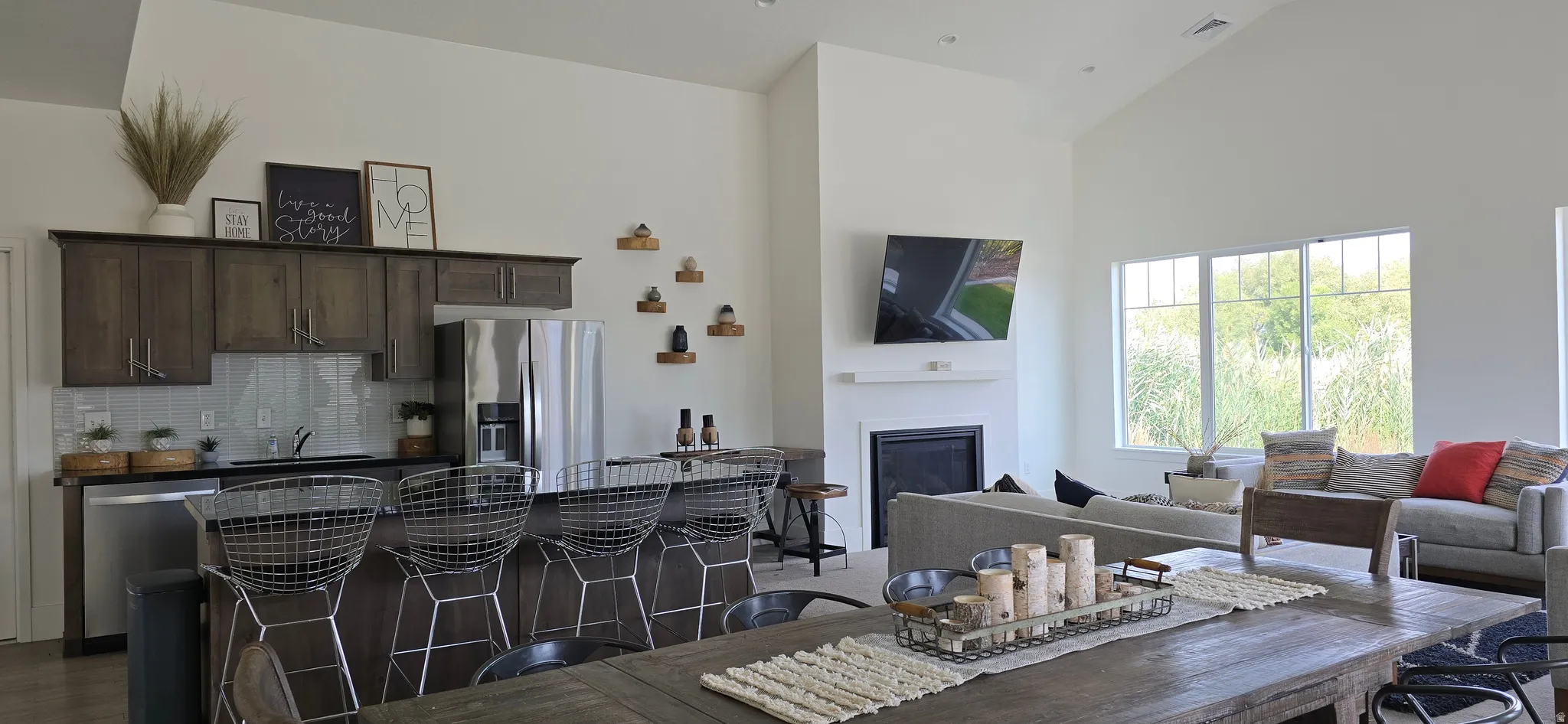 Vaulted ceilings, a built-in fireplace, a breakfast bar, stainless steel appliances, and a tiled backsplash