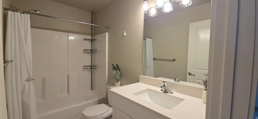 White vanity with integrated sink, polished chrome faucet, and overhead bar lighting