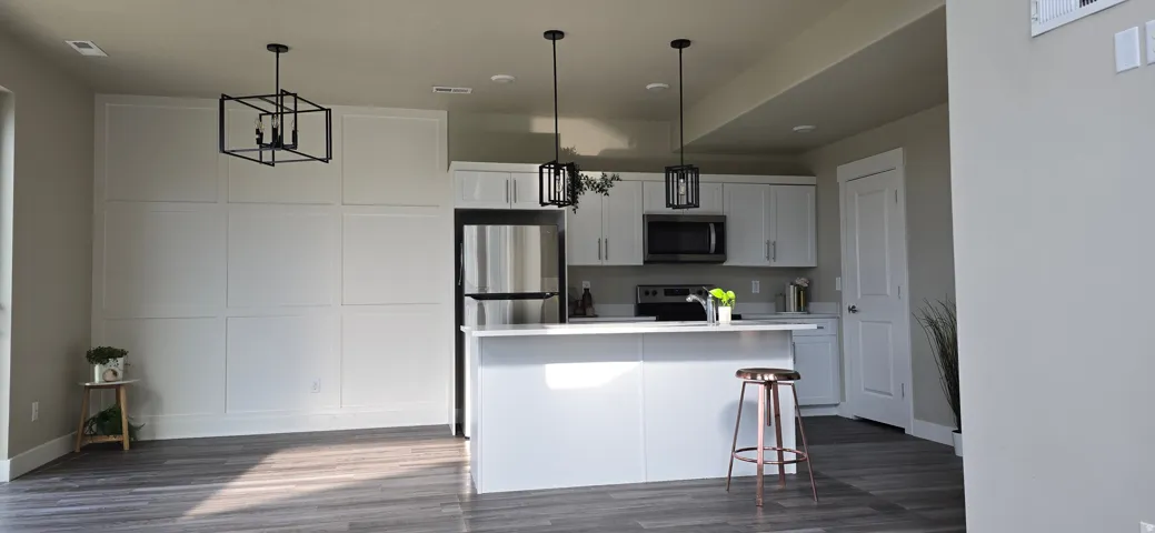 Modern kitchen featuring white cabinetry, stainless steel appliances, and a central island with pendant lighting