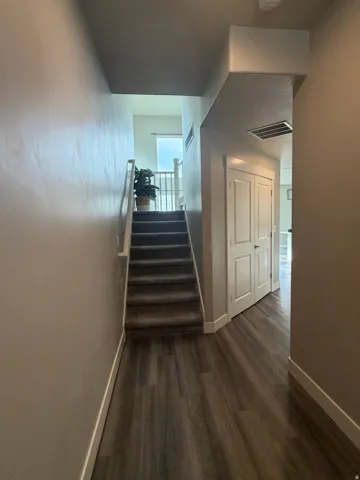 Wood-finish flooring with a carpeted staircase and white railing