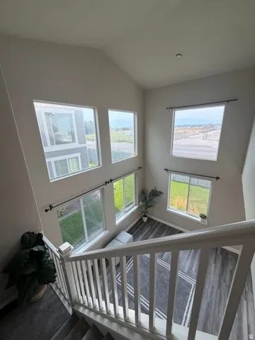 Vaulted ceiling with multiple windows, wood-finish flooring, and white painted railings