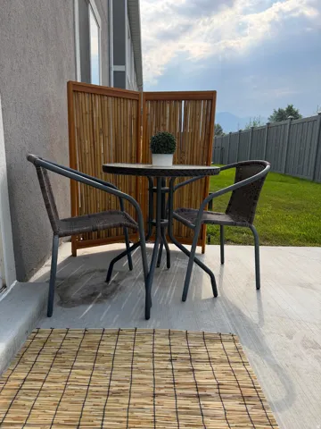 Poured concrete patio with a privacy screen and a manicured lawn