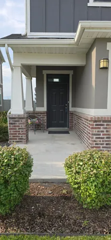 Covered front porch with brick column bases and a dark-paneled entry door