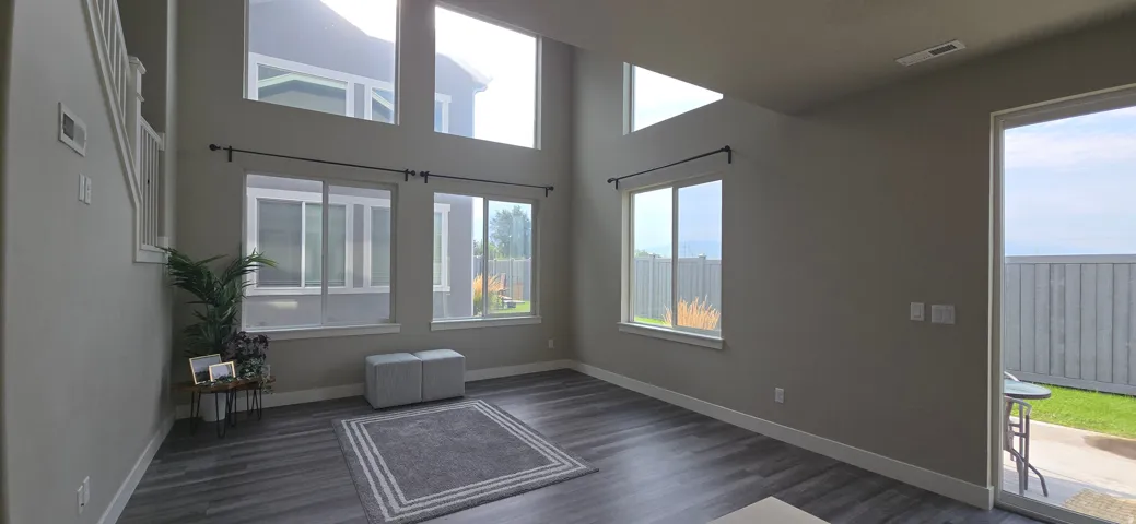 Vaulted ceiling, wood-finish flooring, abundant natural light, multiple windows, and a sliding glass door