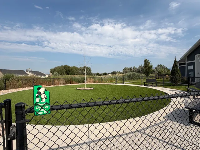 Fenced turf area with a winding concrete path and perimeter landscaping