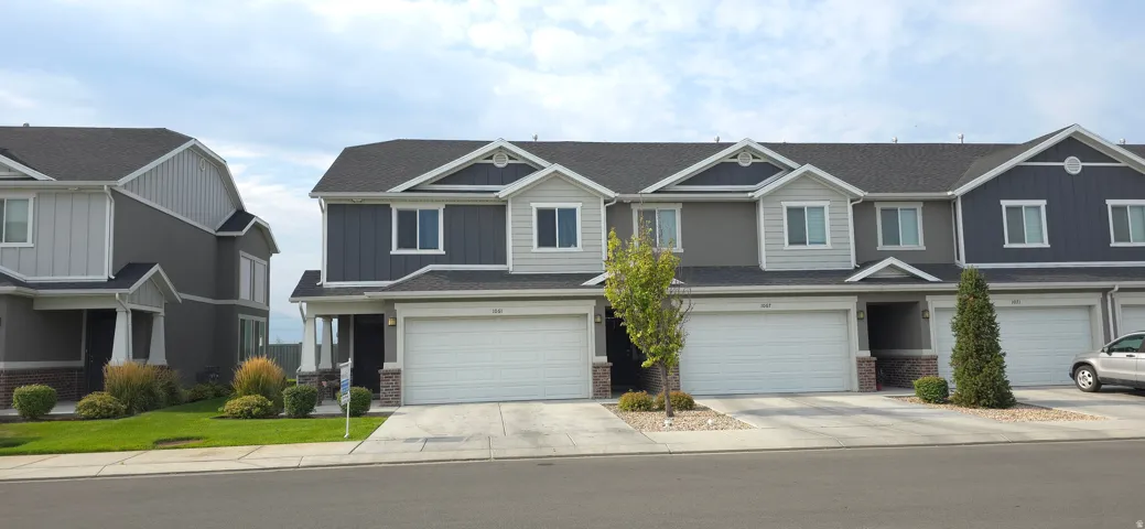 Exterior featuring a two-car garage, dark-toned siding with light trim accents, and a gray shingled roof