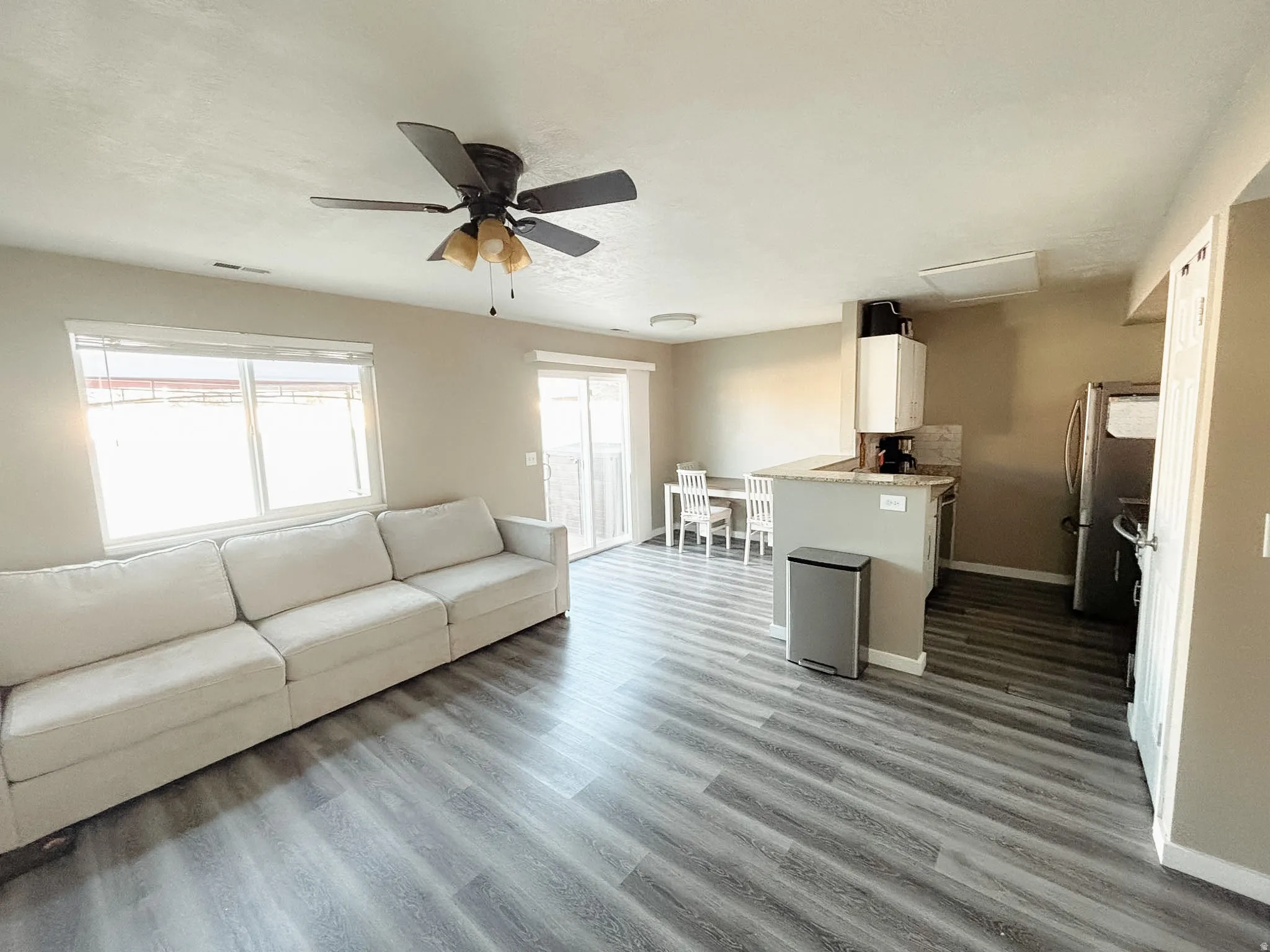 Open-concept living area with wood-finish flooring, a ceiling fan, and a sliding glass door