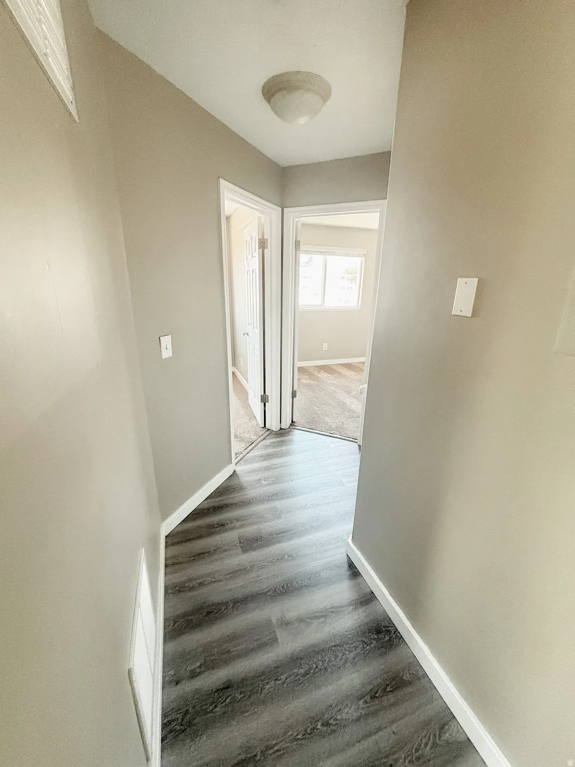 Hallway featuring wood-finish flooring, neutral wall paint, and a ceiling-mounted light fixture