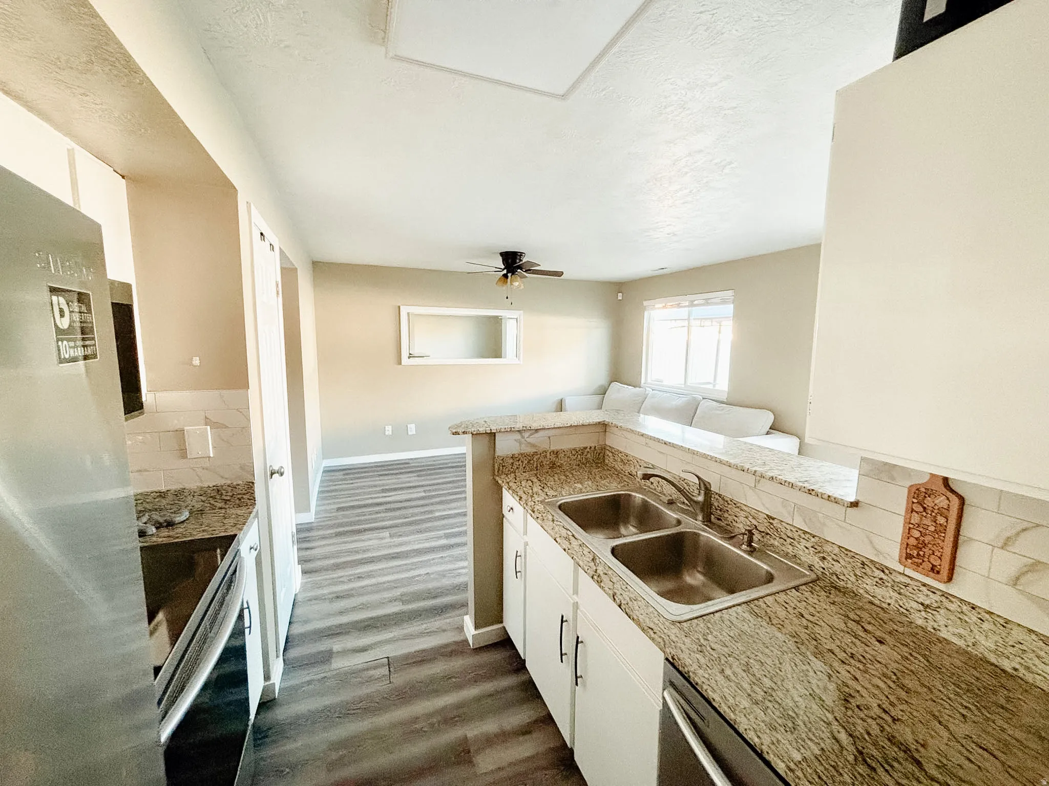 Kitchen featuring granite-look countertops, white cabinetry, a stainless steel sink, and a tiled backsplash