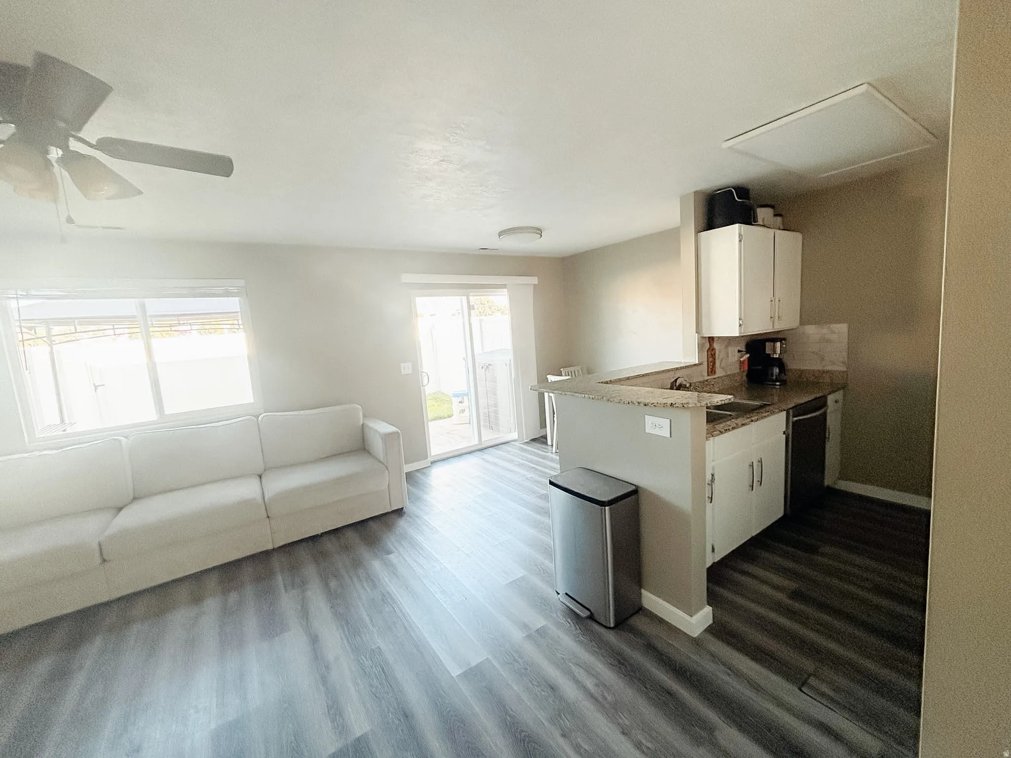 Open-concept living area with wood-finish flooring, a ceiling fan, and sliding glass doors