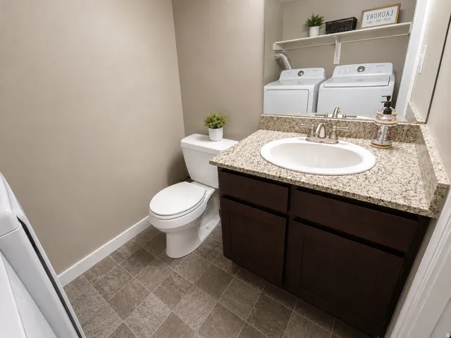 Vanity with a granite-style countertop and undermount sink, dark wood-finish cabinetry, and tiled flooring