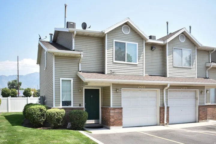 Siding exterior with a dark green entry door, an attached garage, and a white privacy fence