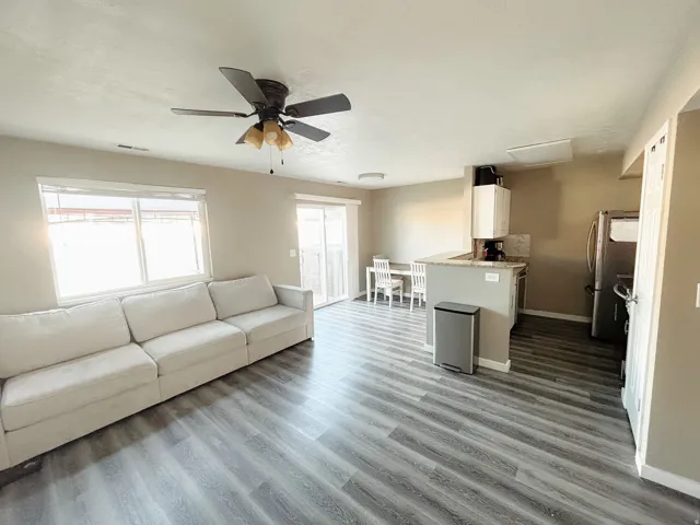 Open-concept living area with wood-finish flooring, a ceiling fan, and a sliding glass door