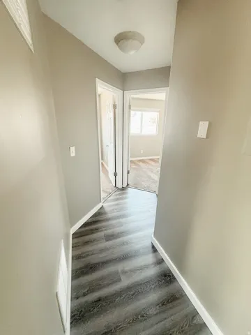 Hallway featuring wood-finish flooring, neutral wall paint, and a ceiling-mounted light fixture