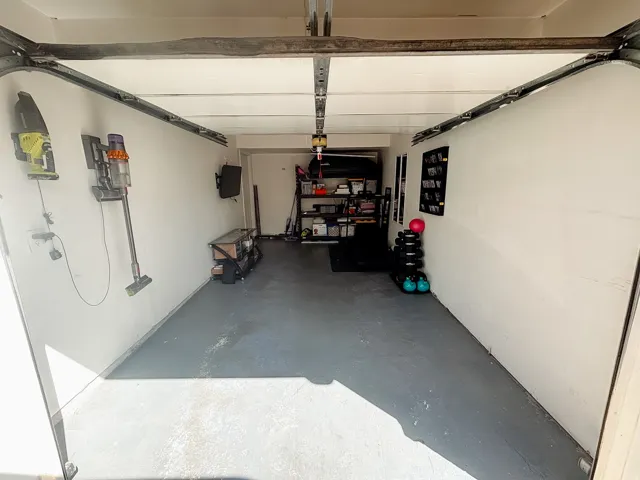 Garage space with painted concrete flooring and overhead lighting