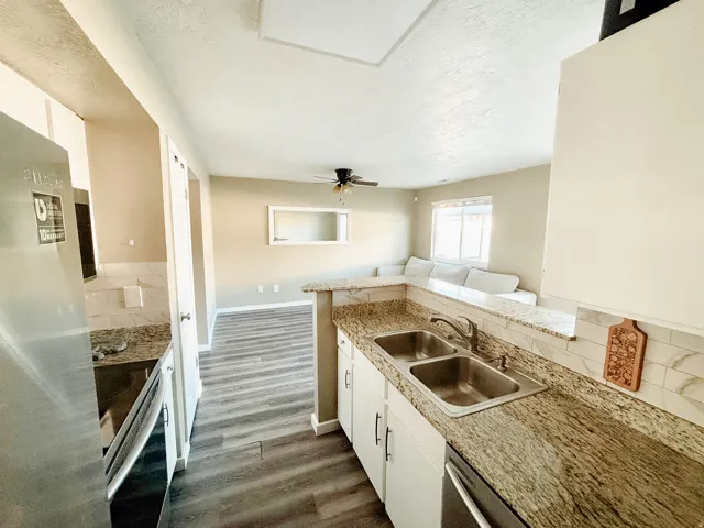 Kitchen featuring granite-look countertops, white cabinetry, a stainless steel sink, and a tiled backsplash