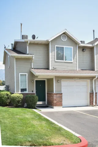 Siding exterior with brick accents, attached garage, and a dark green entry door