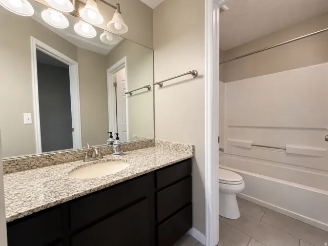 Bathroom featuring a dark wood-finish vanity with a light granite countertop, an undermount sink, and a chrome faucet