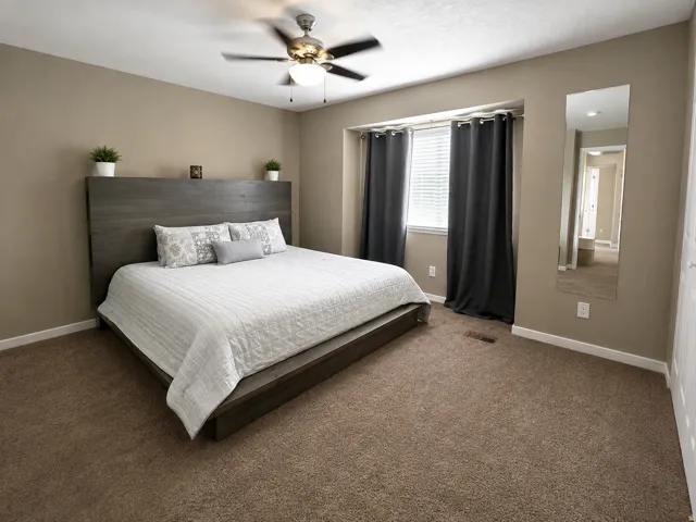 Neutral wall paint, carpeted flooring, window with blinds, and a ceiling fan with integrated lighting
