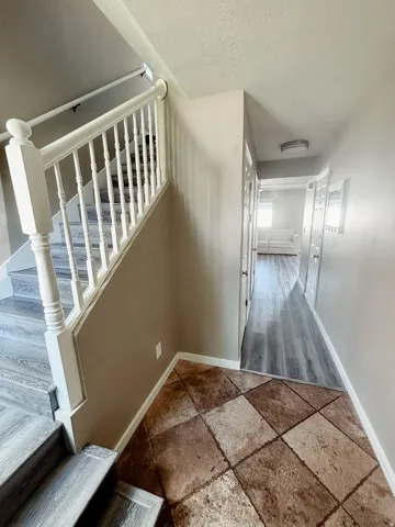 Foyer featuring a tiled entry, staircase with white balusters, and wood-finish flooring extending into the hall