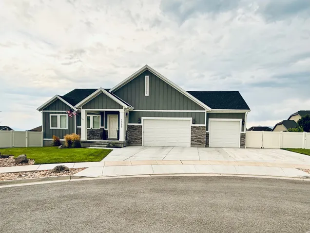 Ranch-style exterior with contrasting vertical and horizontal siding, stone veneer accents, and a three-car attached garage