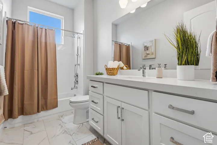 White cabinetry with brushed nickel hardware, expansive vanity countertop, integrated sink, large wall-mounted mirror, and tile flooring
