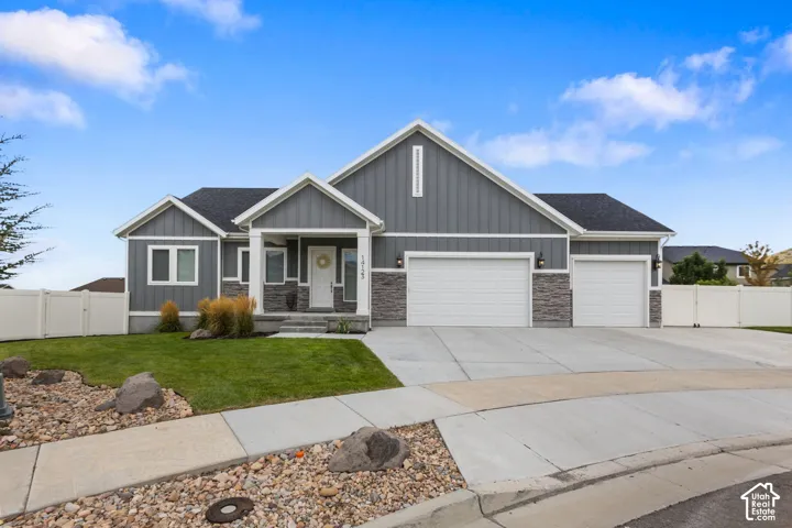 Contemporary exterior featuring gray siding, stone accents, multiple gables, a covered entry, and a multi-car garage
