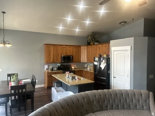 Kitchen featuring wood cabinetry, an island with stone-finish countertops, and recessed lighting.