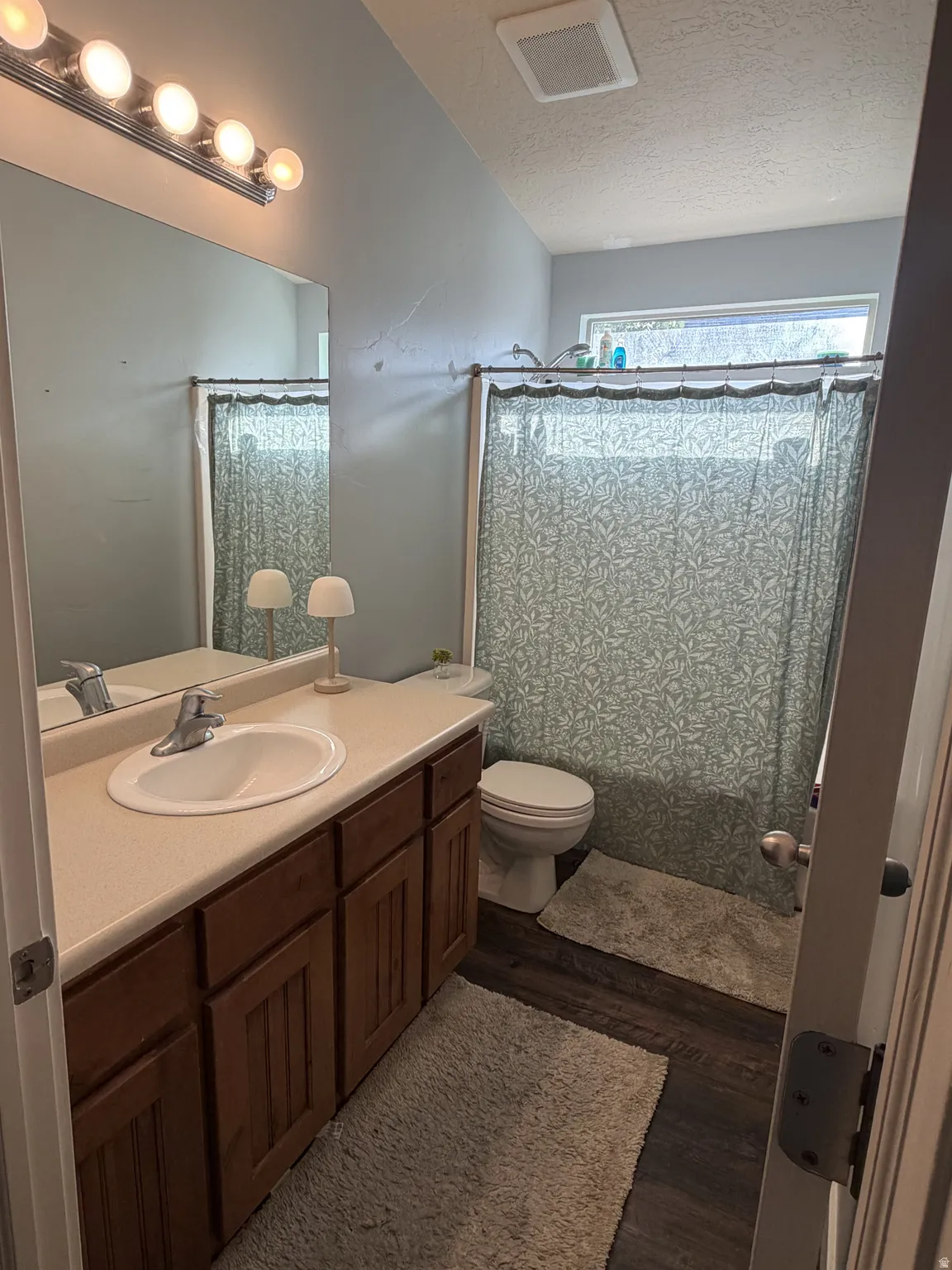 Vanity with built-in sink, wood-finish cabinetry, and a light-colored countertop