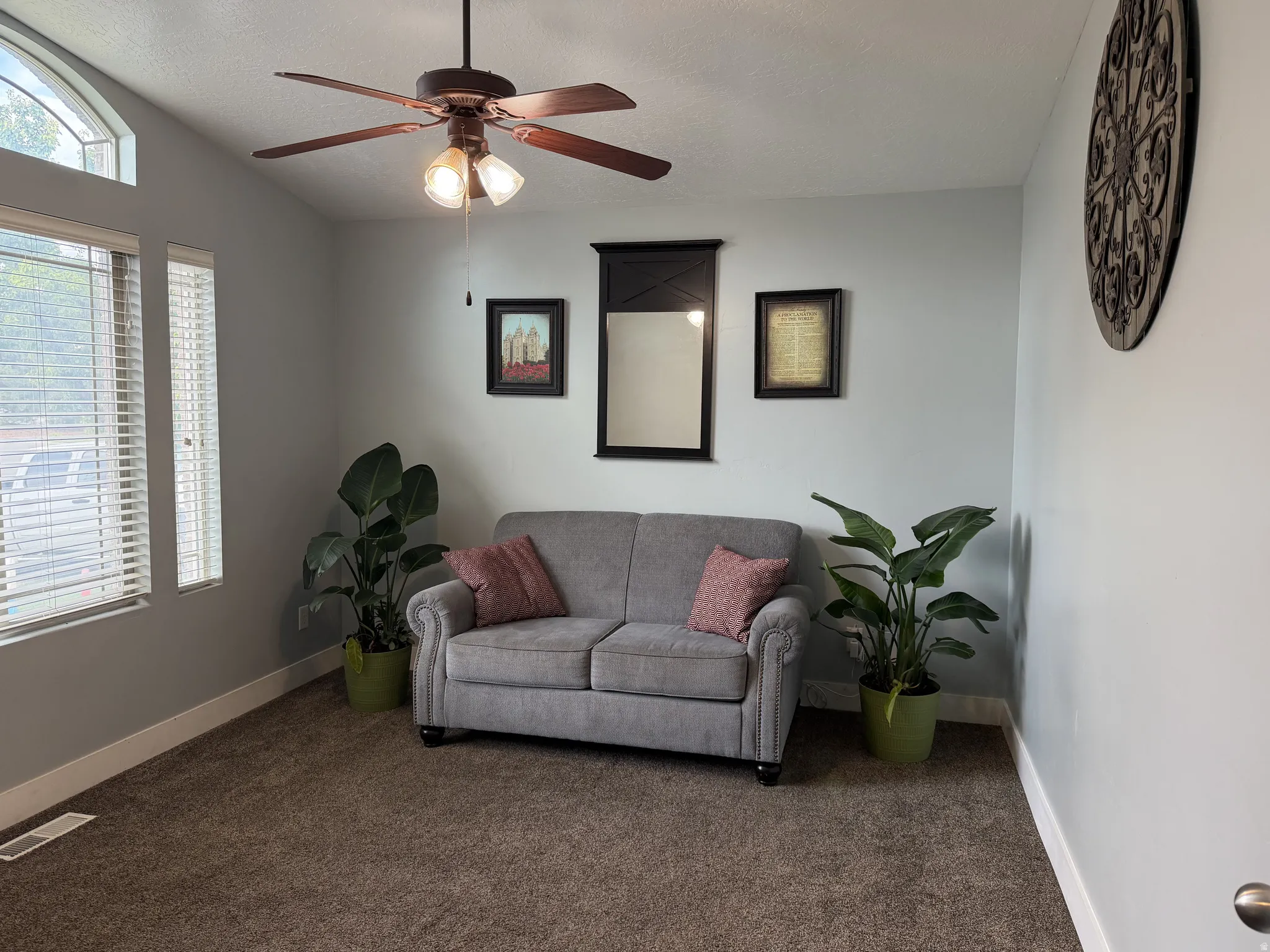 Carpeted room with a ceiling fan, arched transom window, and window blinds