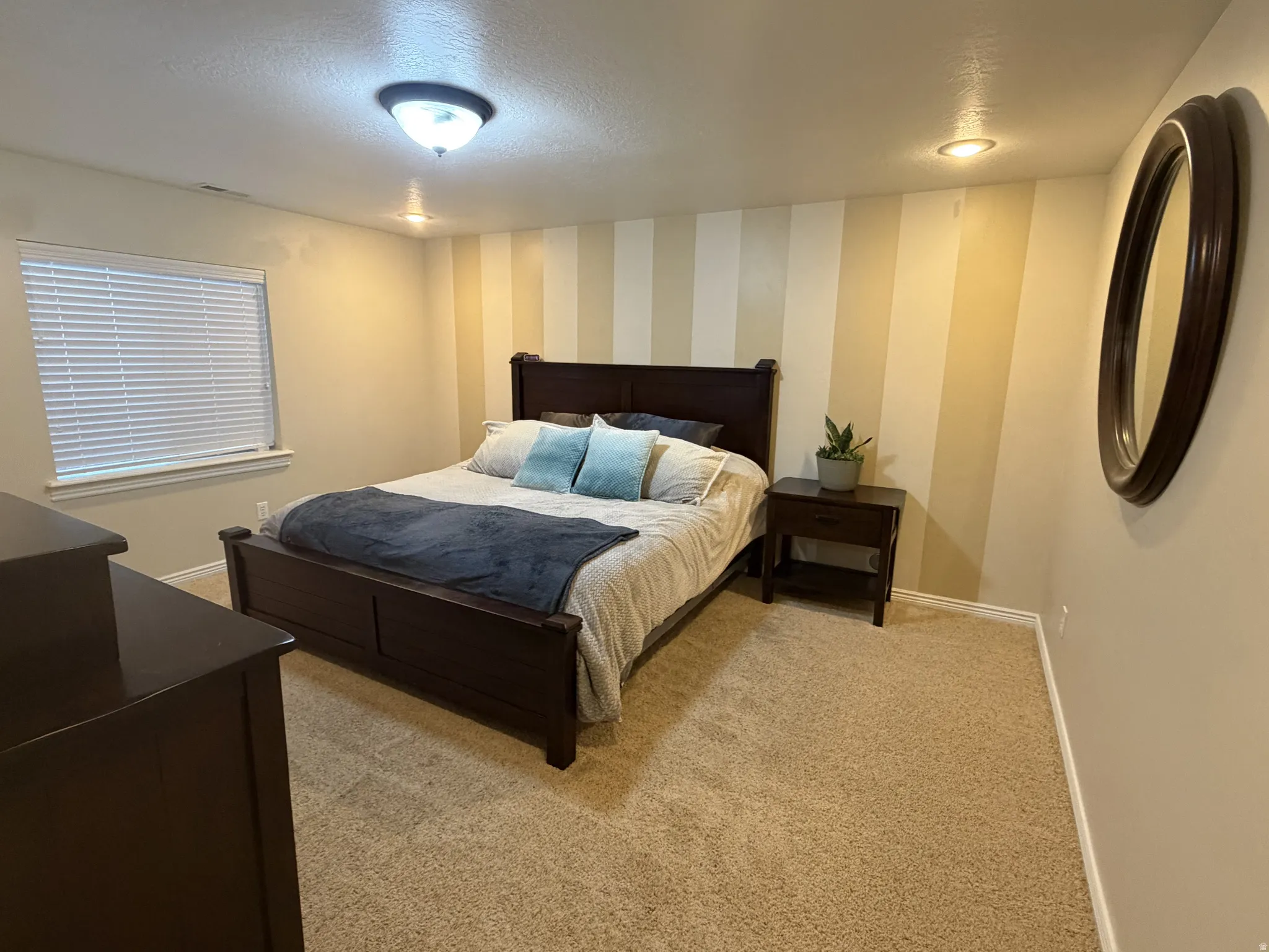 Primary suite #2. Plush carpet flooring, recessed lighting, ceiling-mounted light fixture, window with blinds, and striped accent wall