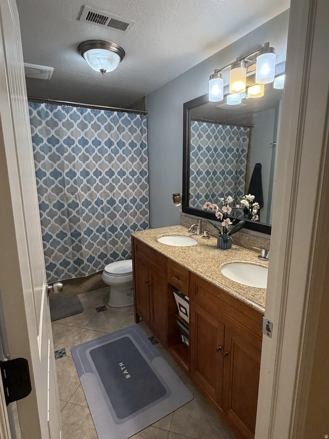 Primary suite Bath #2. Dual vanity bathroom , ^ foot soaker tub. featuring warm wood cabinetry, granite countertops, and brushed nickel fixtures