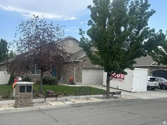 Stucco and brick exterior with arched window detail, integrated three-car garage, and established front yard landscaping. New mailbox with lock.