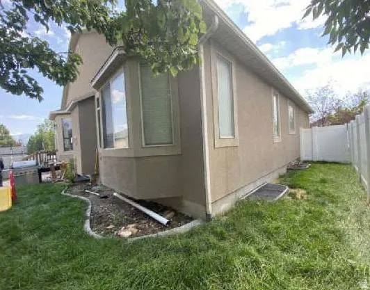 Stucco exterior with multiple windows, bay window feature, and white fencing