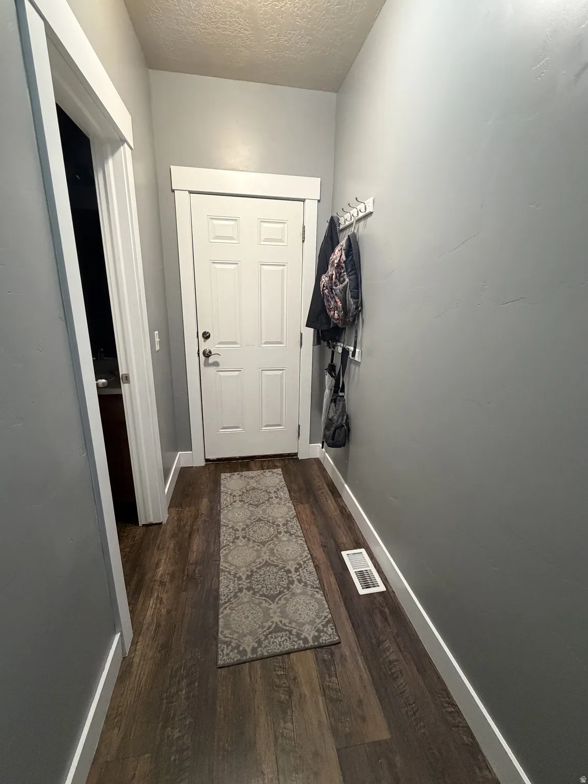 Wood-finish flooring, white paneled door, and neutral wall paint