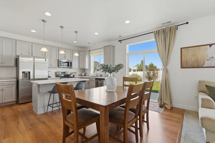 Contemporary kitchen with light grey cabinetry, stainless steel appliances, and a central island with countertop seating