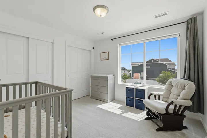 Carpeted room with a large window, white sliding closet doors, and a flush mount ceiling light fixture
