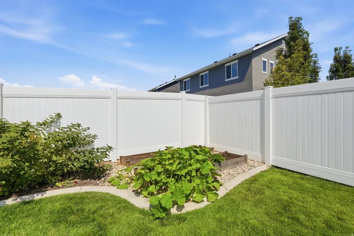 Manicured lawn with a white privacy fence and a raised garden bed