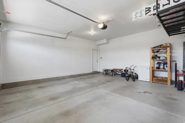 Attached garage with a concrete floor, white walls, overhead lighting, and an overhead garage door track system