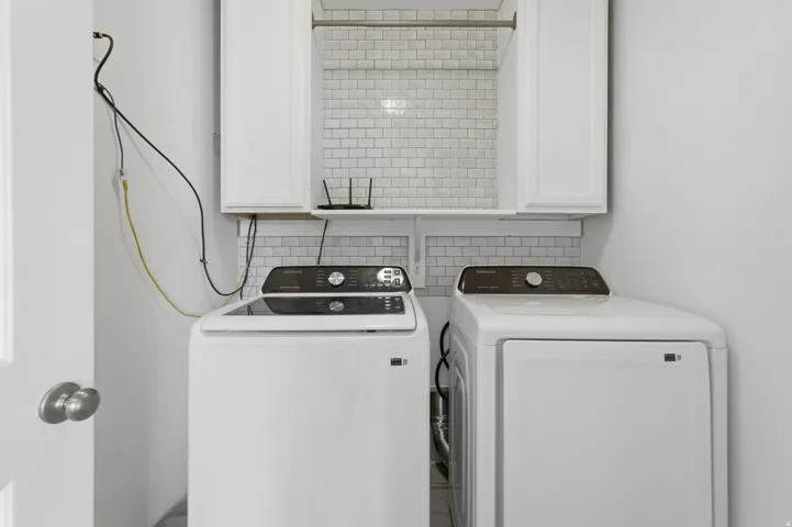 White cabinetry with matte black pulls, subway tile backsplash, and a wall-mounted drying rod