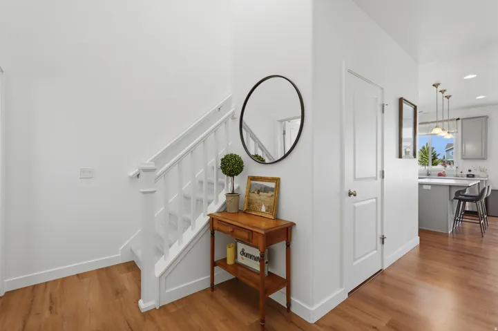 Wood-finish flooring, white painted walls, and a staircase with white balusters