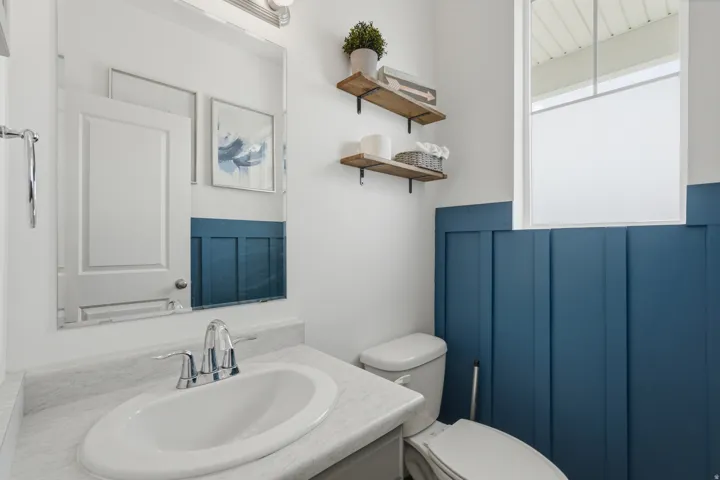White vanity with an integrated sink, chrome faucet, and full-width mirror