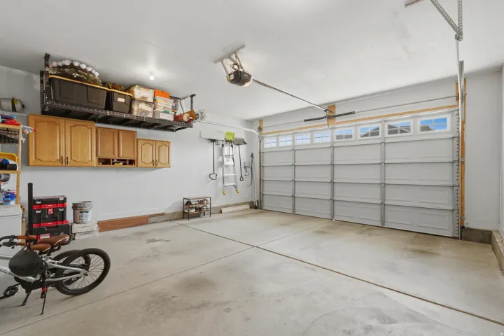 Concrete flooring, overhead lighting, and an automatic garage door with upper window panels