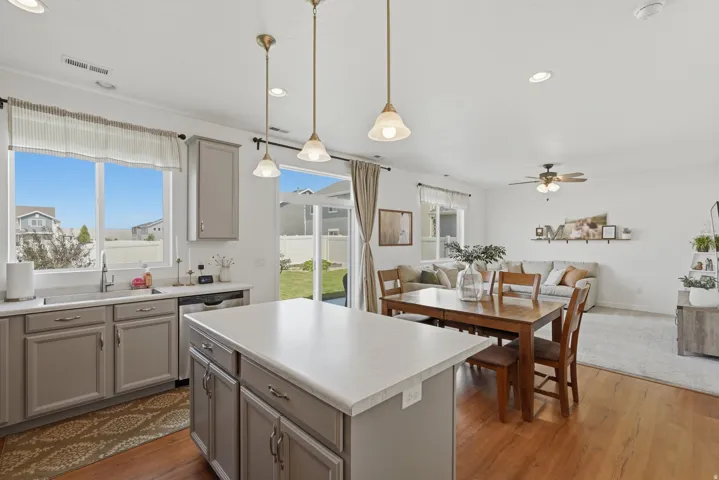 Kitchen island with light-toned countertop, gray cabinetry, and pendant lighting